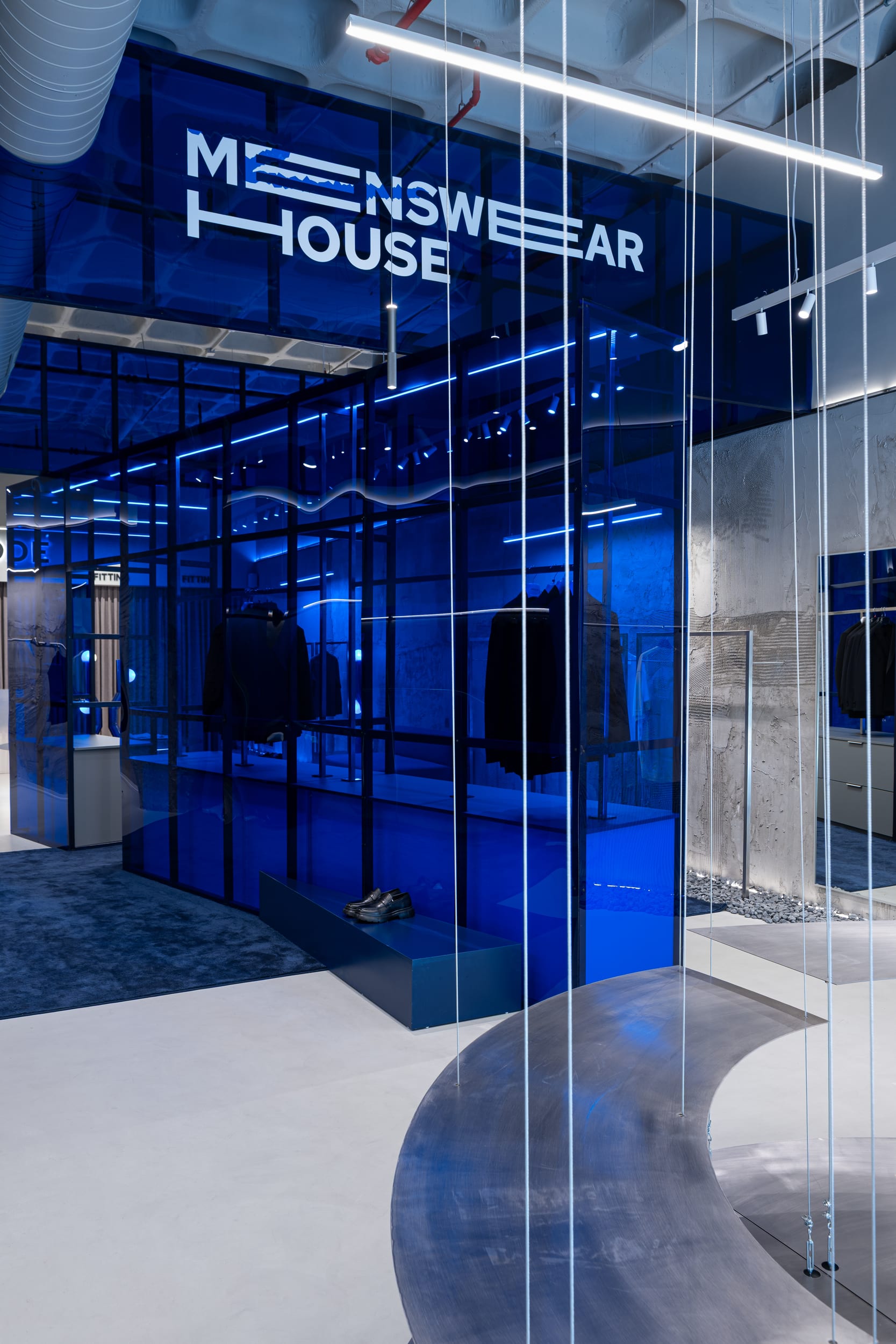 Blue mirrored glass volume with the Menswear House signage and fitting rooms
