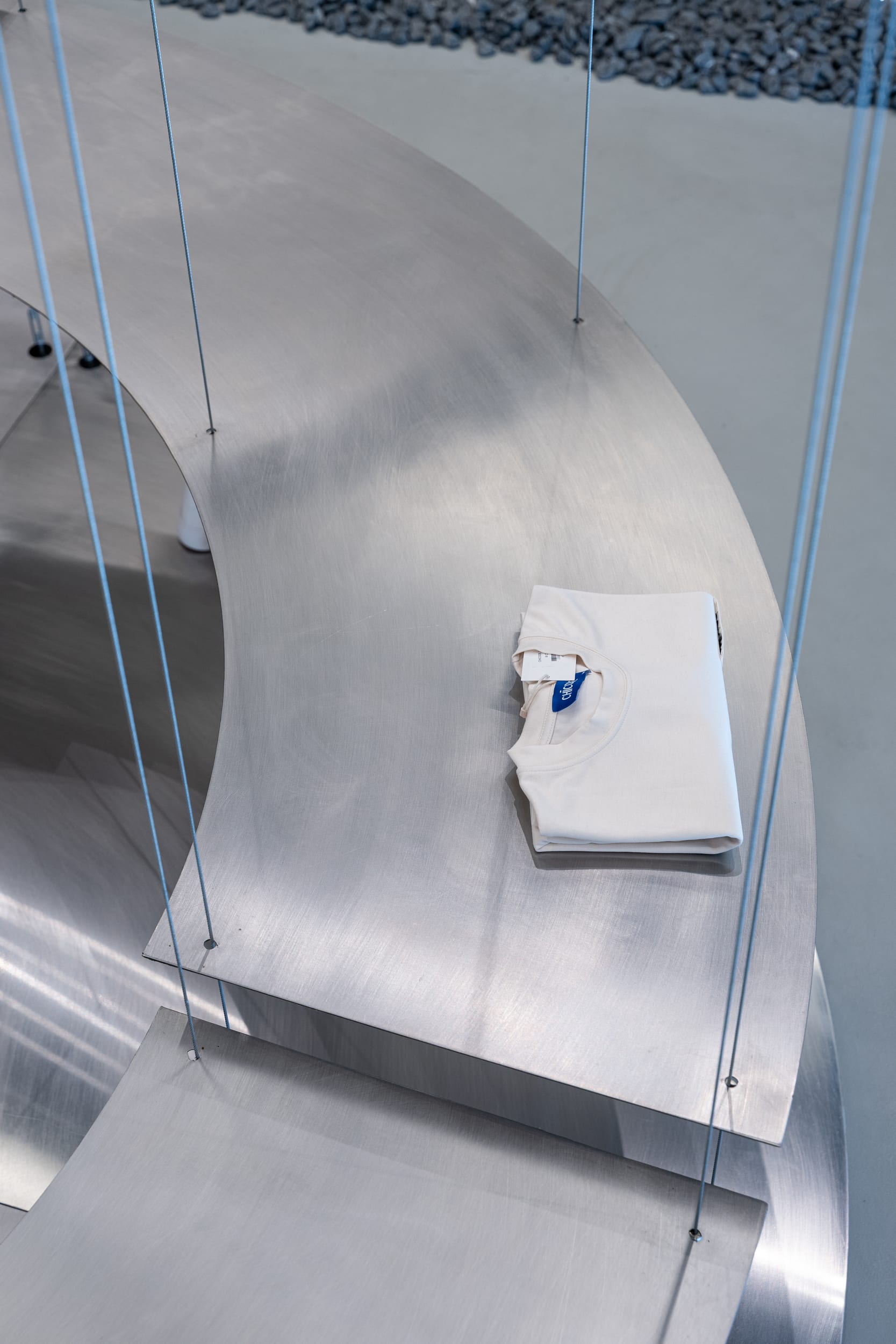 Detail of the brushed-steel display table with a folded CHICODE garment